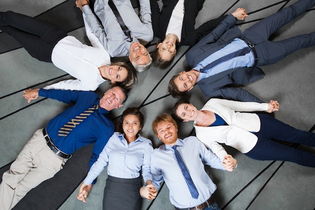 Business People Lying on Floor and Holding Hands