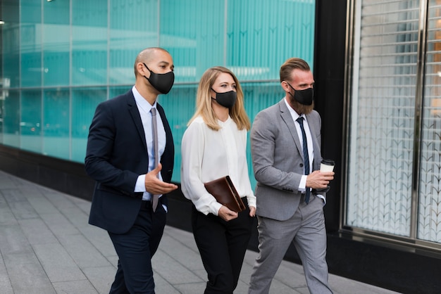 Деловые люди в медицинских масках, идущие в офис