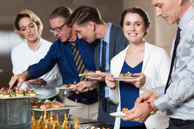 Free photo business people taking snacks from buffet table