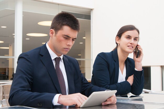 Business people using tablet and calling on phone at desk