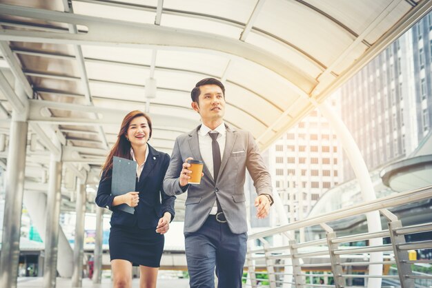 Business people walking through passage office. Smiling to each other.