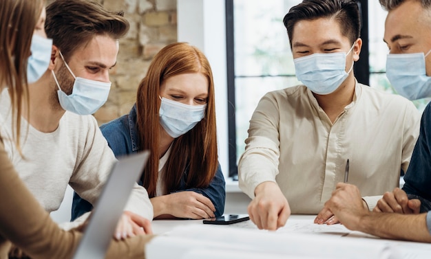 Business people wearing medical masks while discussing a project