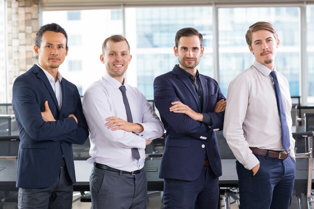 Business people with arms crossed and one with hands in pockets