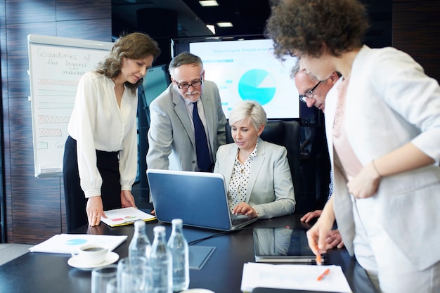 Business people with report working at laptop