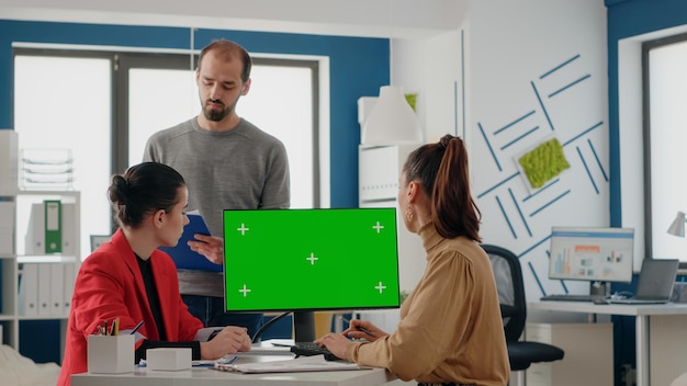 시작 사무실에서 녹색 화면으로 컴퓨터에서 작업하는 비즈니스 사람들. 동료들이 팀워크를 하고 목업 템플릿과 배경이 있는 격리된 크로마 키에 대해 토론합니다.