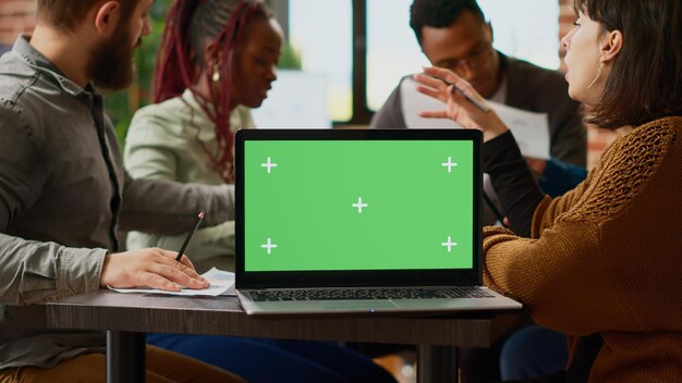 Business people working with paperwork and greenscreen on laptop, planning collaboration. Using blank mockup template with chroma key display and copyspace background. Close up.