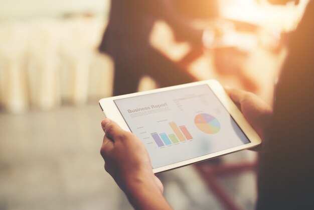 Business person hand holding financial statistics displayed on t