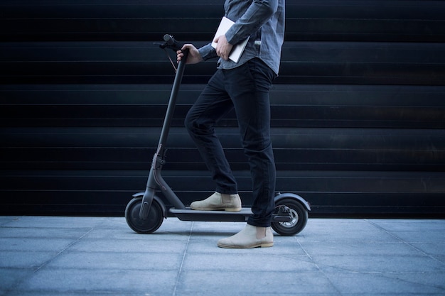 Business person with tablet computer on his electric scooter commuting vehicle