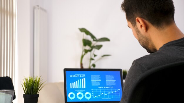 business person working on his laptop looking at chart data in his living room