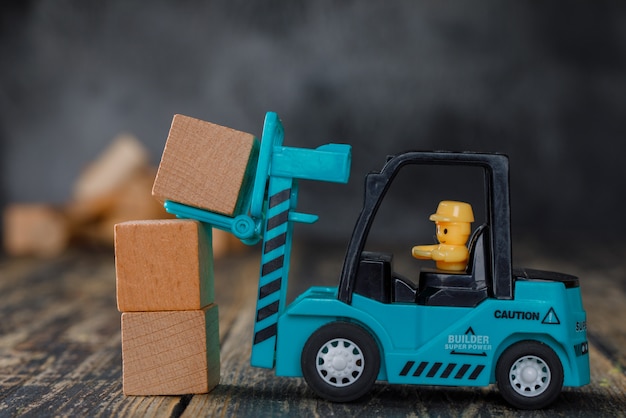 Free photo business planning concept side view. forklift truck stacking wooden blocks.