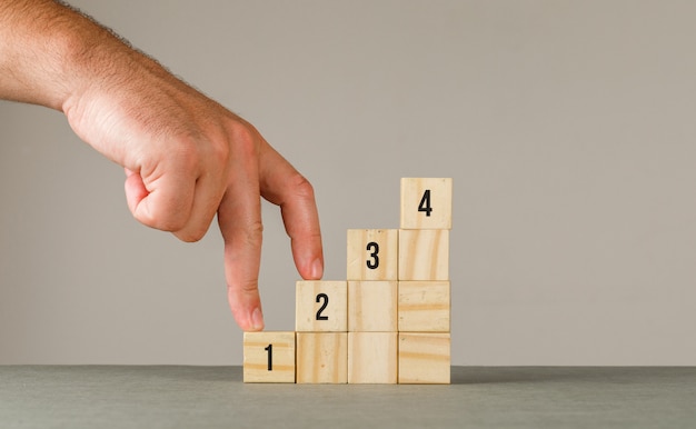 Business strategy concept on grey and white wall side view. man putting fingers on step stairs.