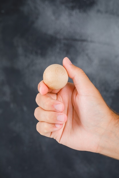 Business strategy concept side view. hand holding wooden sphere.