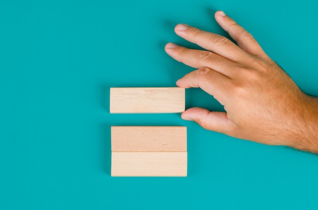 Business strategy concept on turquoise table flat lay. hand pulling or placing wooden block.