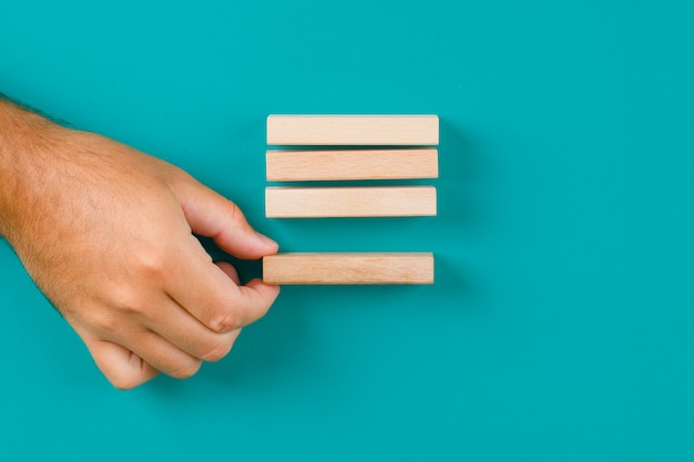 Business strategy concept on turquoise table flat lay. hand pulling or placing wooden block.