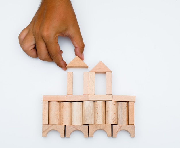 Business strategy concept on white background flat lay. man building castle from wooden blocks.