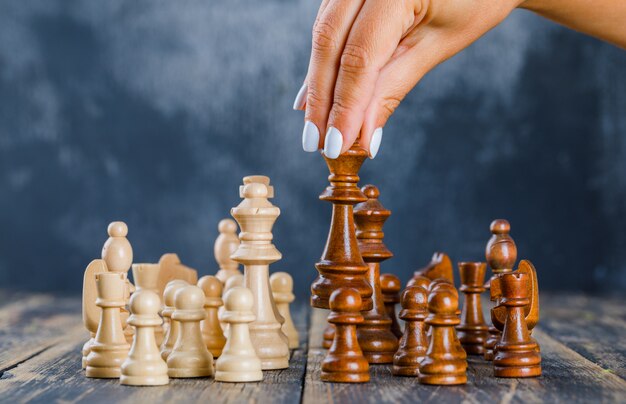 Business strategy concept with chess figures on dark and wooden surface