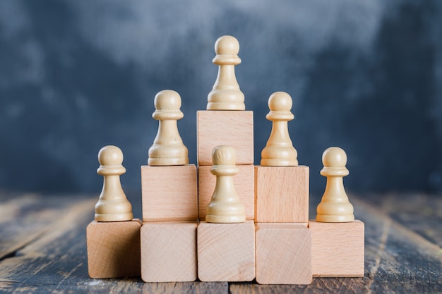 Концепция бизнес-стратегии с шахматными фигурами на игрушечных деревянных лестницах