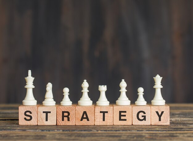 Business strategy concept with chess pieces on wooden cubes on wooden table side view.