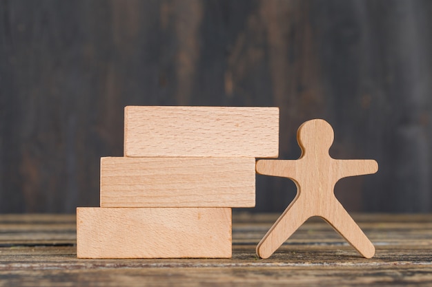 Business strategy concept with wooden blocks, human figure on wooden table side view.