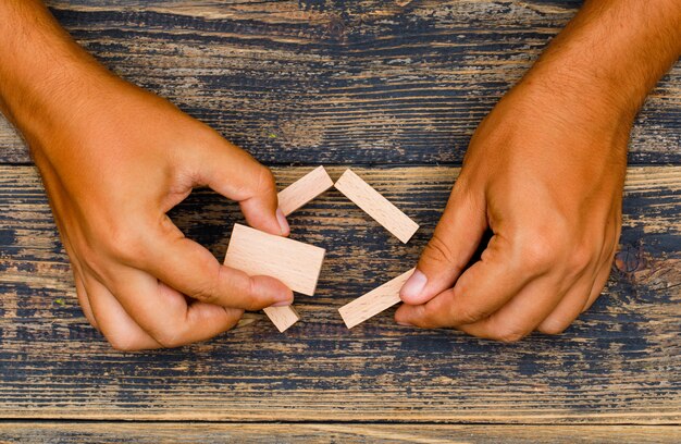 Business strategy concept on wooden background flat lay. hand holding wooden blocks.