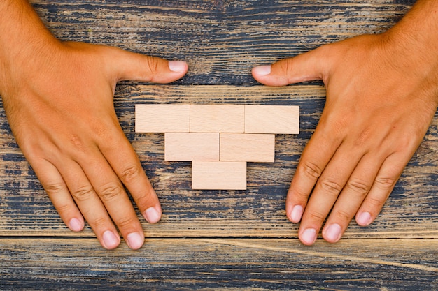 Business strategy concept on wooden background flat lay. hands protecting wooden blocks.