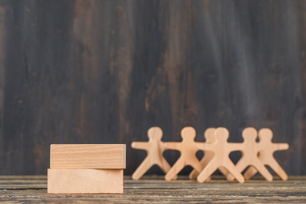 Business success concept with wooden blocks, human figures on wooden table side view.