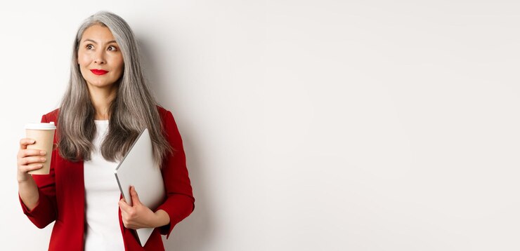 Free Photo business successful asian businesswoman with grey hair drinking coffee and standing with laptop look