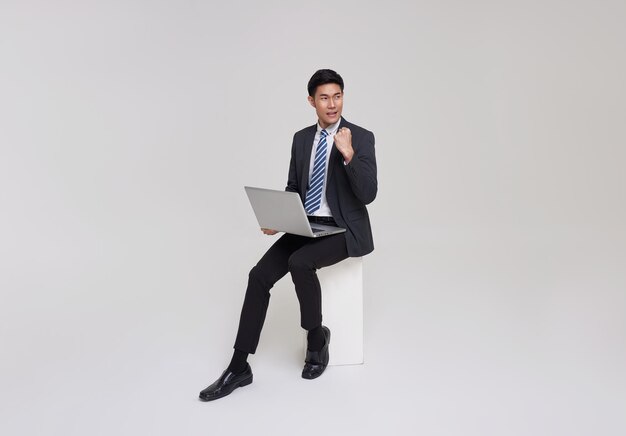 비즈니스 성공적인 아시아 사업가 컴퓨터를 사용 하 고 앉아 웃 고 노트북 작업