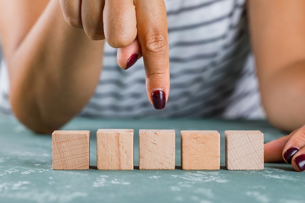 Business target concept side view. woman showing wooden cube.