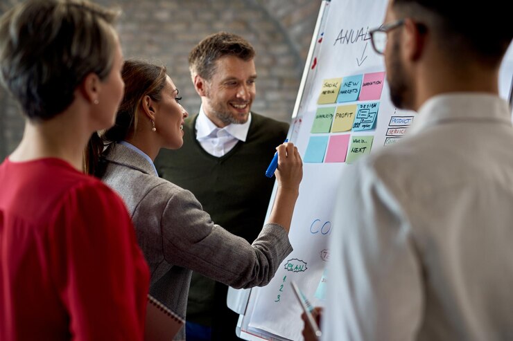Free Photo business team cooperating while making new plans on a whiteboard in the office focus is on businesswoman writing the notes