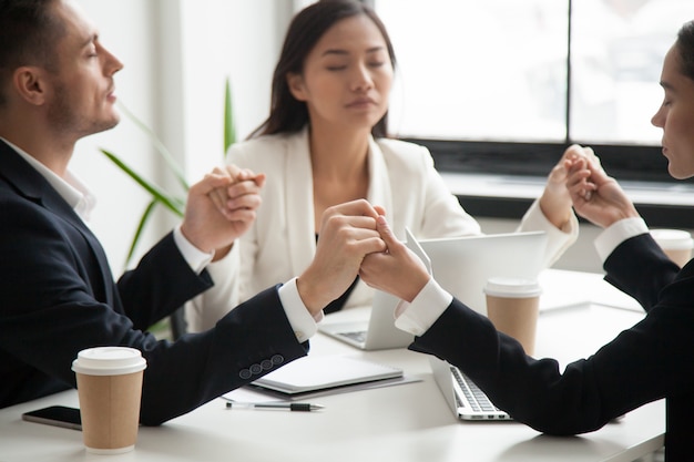 Business team holding hands praying for success