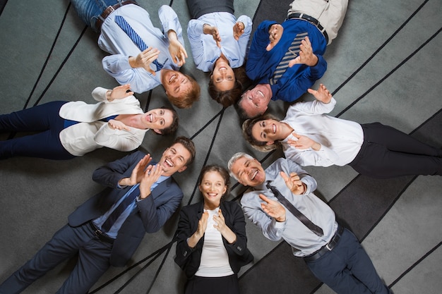 Free photo business team lying on floor and clapping