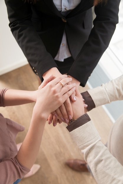 Foto gratuita il concetto di lavoro di squadra di affari, vista superiore delle mani si è unito insieme, verticale