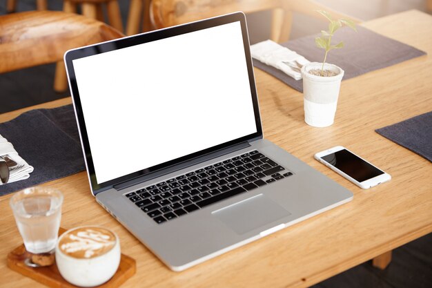 Business, technology and communication concept. Minimalistic workspace with modern laptop computer with white blank screen