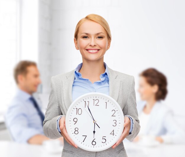 Business and time concept - attractive businesswoman with wall clock