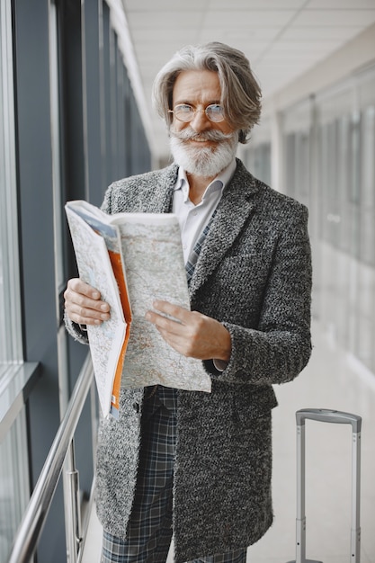 Business trip. Corporate and people concept. Male in a gray coat. Senior with a map.