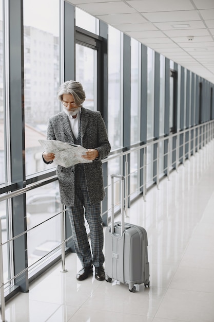 Business trip. Corporate and people concept. Male in a gray coat. Senior with a map.