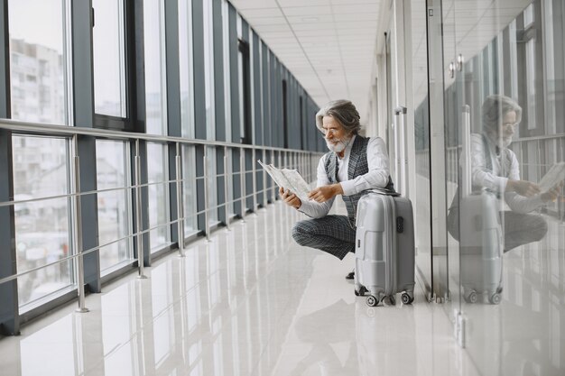 Business trip. Corporate and people concept. Male in a gray coat. Senior with a map.