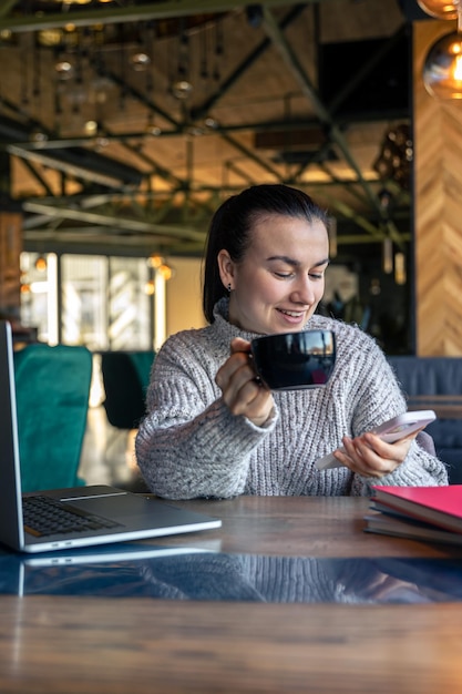 Free photo business woman in a cafe with a laptop drinks tea