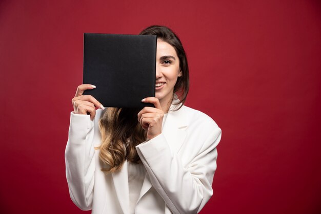 Business woman covering her face with a notebook 