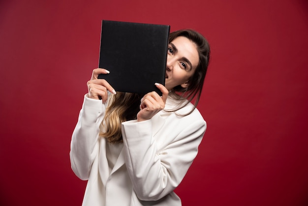 Business woman covering her face with a notebook 