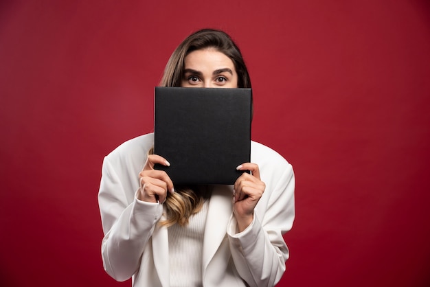 Business woman covering her face with a notebook 