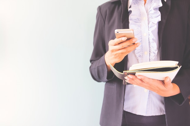 Business woman in dark suit holding mobile phone and notebook, Business concept with copy space