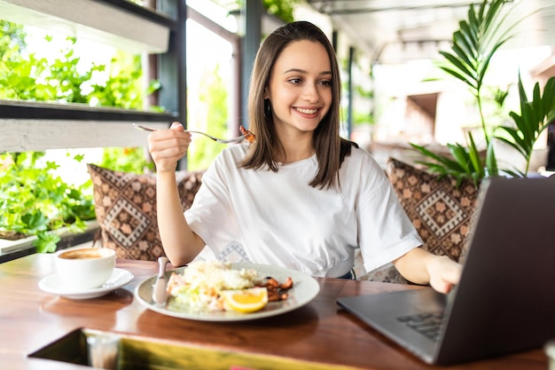 Business woman eating lunch and working on laptop