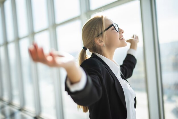 ビジネスの女性は興奮して手を上げた腕に手を握って近代的なオフィスで勝利を祝う