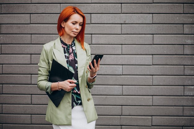 Business woman in green suit standing with folder