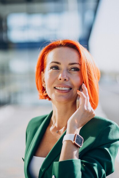 Business woman in green suit using phone outside the street