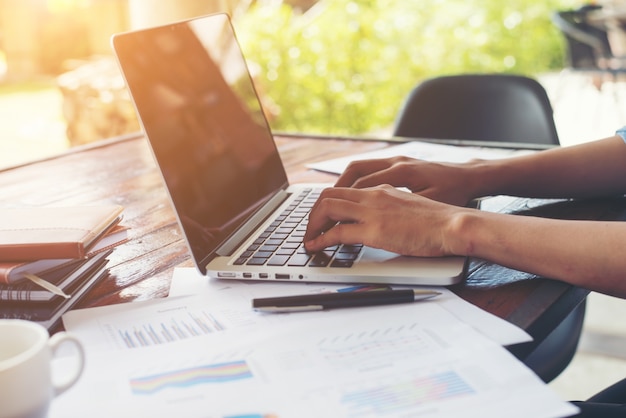 Business woman hand typing on laptop keyboard with Financial cha