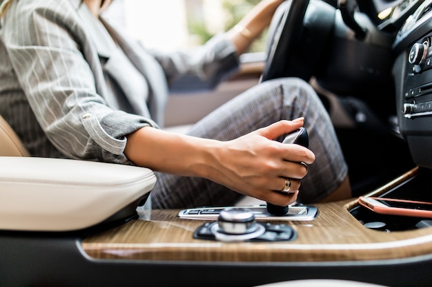 Business woman hand using a car automatic gear. Woman driving concept