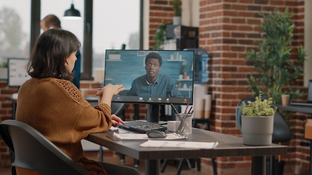 Business woman having discussion with man on video call at desk. Entrepreneur using online remote conference on computer to talk to colleague about project planning and presentation.